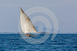 Malagasy fisher on sea in traditional handmade dugout wooden sailing boat