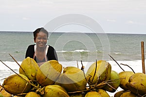 Malagasy woman selling coconuts on the beach