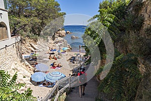 Malaret cove with a excursionist girl and lot of people on the sand in Begur