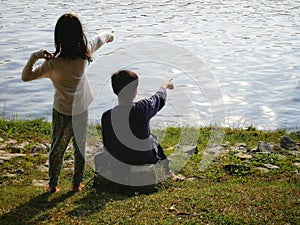 A Malay Boy and girl looking at the lake and point their finger to the lake