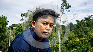 Malay man model wearing a traditional Baju Melayu with green nature background