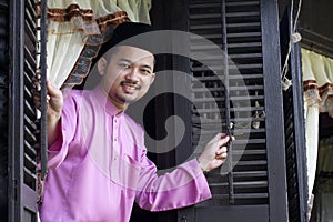 Malay muslim man open a traditional window