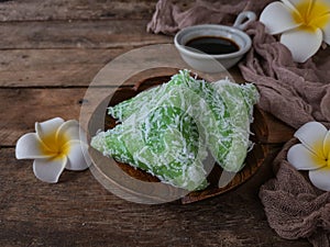 A Malay traditional dessert called Kuih Lopes on plate with flower and cloth decoration over wooden background