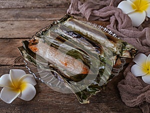 A Malay traditional dessert called Pulut Panggang on plate with flower and cloth decoration over wooden background