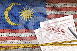 Malaysia flag and Health insurance claim form with covid-19 stamp. Coronavirus or 2019-nCov virus concept