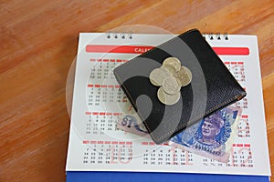 Malaysia ringgit and coins on calendar background.