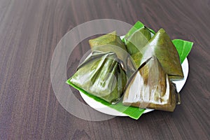 Malaysian Delicacies Kuih Koci in Banana Leaf on Wooden Desk.