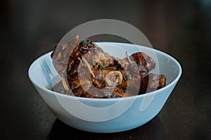 Malaysian dish of Ayam Masak Kicap or deep fried chicken in black soy gravy in a white bowl