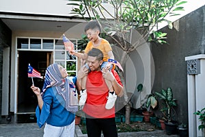 Malaysian family holding malaysia flag in front of their house