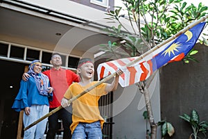 Malaysian family holding malaysia flag in front of their house