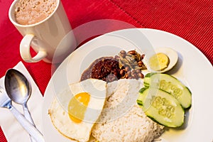 Malaysian Food - Nasi Lemak and Frothy Teh Tarik on a red background. Both dishes are unofficially the national breakfast dish