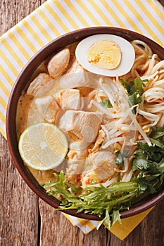 Malaysian laksa soup with chicken close up in a bowl. Vertical t
