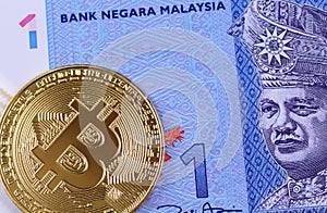 A Malaysian one ringgit bank note with a gold bitcoin