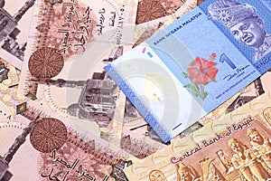 A Malaysian ringgit on a background of Egyptian one pound bank notes