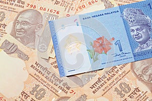 A Malaysian ringgit on a background of Indian ten rupee bank notes