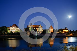 Malbork castle in Poland at night with reflection in Nogat river photo