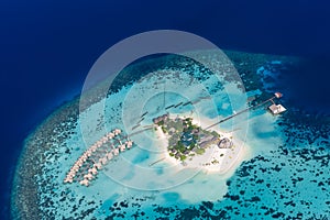 Maldives aerial view landscape. Coral reef and blue sea with white sandy island beach and luxury villas