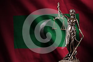 Maldives flag with statue of lady justice and judicial scales in dark room. Concept of judgement and punishment