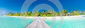 Maldives island beach panorama. Palm trees and beach bar and long wooden pier pathway. Tropical vacation and summer holiday banner