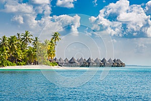 Maldives island, luxury water villas resort and wooden pier. Beautiful sky and clouds and beach background for summer vacation