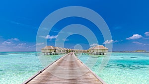 Maldives island, luxury water villas resort and wooden pier. Beautiful sky and clouds and beach background for summer vacation