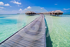 Maldives island luxury water villas resort and wooden pier. Beautiful sky and clouds and luxury beach background