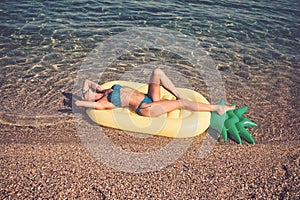 Maldives or Miami beach water. Girl sunbathing on beach with air mattress. Summer vacation and travel to ocean.