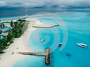 Maldives tropical beach with pier and boats in blue ocean. Travel vacation concept. Aerial view