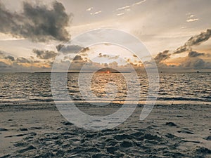 Maldives, tropical paradise. Sunset in the ocean with small islands on the horizon.