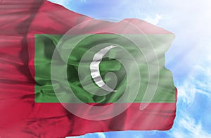 Maldives waving flag against blue sky with sunrays