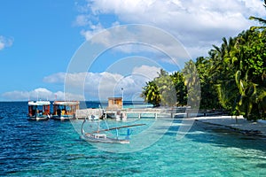 Maldivian dhoni and sailing boats at jetty landing stage of little harbor  in turqouise blue indian ocean paradise island