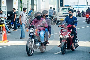 Maldivian men in masks riding motobikes  on the street during covid-19