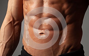 Male abdominal muscles closeup with sweat drops after exercise
