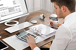 Accountant Calculating Tax At Desk