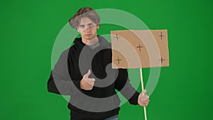 A male activist holds a blank poster and shows a thumbs up. A young man in casual clothes holds a placard on a green