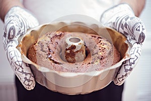 Male adult person holding out of the oven homemade bundt cake