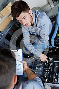 male aero engineer with clipboard working in cockpit