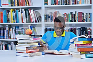 Male african american college student reading in library
