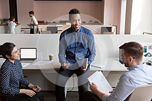 Male african american executive discussing paperwork with diverse colleagues