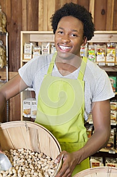 Male African American store clerk holding basket of peanuts