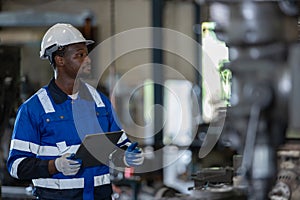 Male African American workers wearing uniform safety and hardhat using tablet working at machine in factory Industrial.