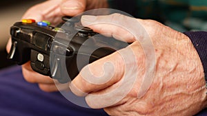 Male aged gamer theme. close-up of the hand of a pensioner who actively uses the joystick is playing video games. Elderly man hobb