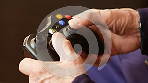 Male aged gamer theme. close-up of the hand of a pensioner who actively uses the joystick is playing video games. Elderly man hobb