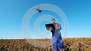 Male agronome is managing a drone with his computer
