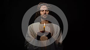 Male alike Jesus in crown of thorns blowing on candle, mortal people sins, god