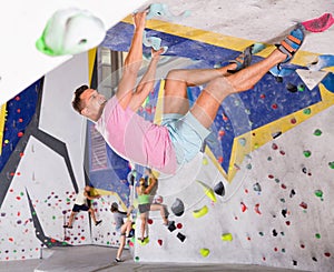 Male alpinist practicing indoor rock-climbing on artificial boulder without safety belts