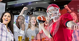 Male american footballer about to throw ball against excited spectators at bar
