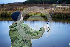 Male angler catches on a spinning fish in cold water in the offseason.