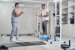 Male with ankle weights exercising on balance trainer