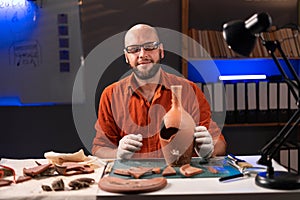 Male archeologist working late night in office looking at camera